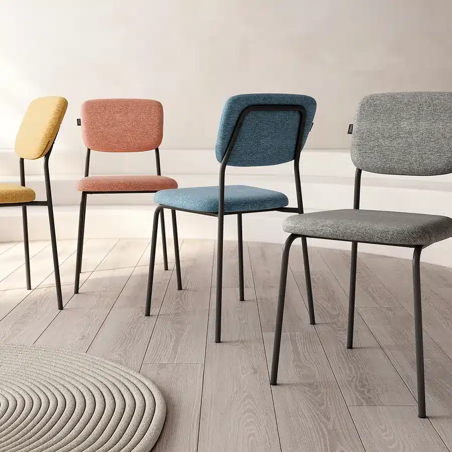 Sillas de comedor tapizadas en amarillo, rosa, azul y gris con patas de metal negro